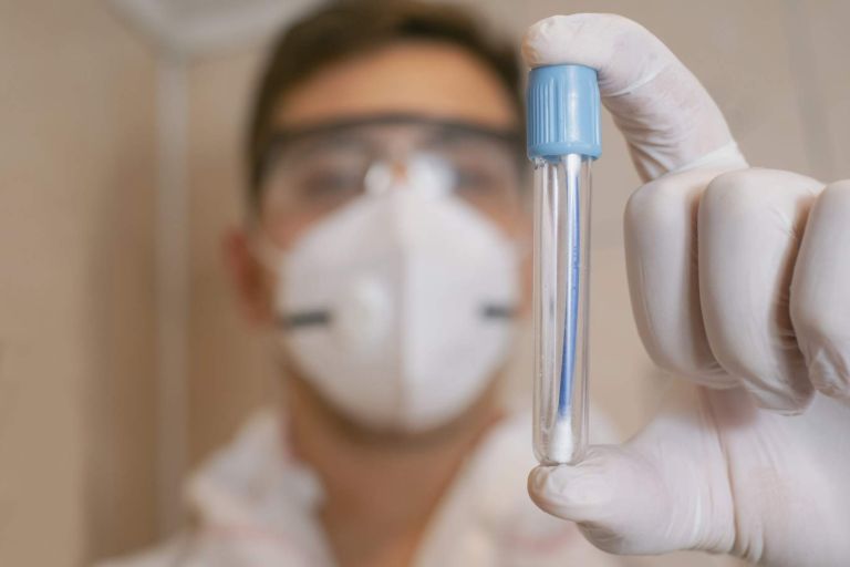 The hands of a scientist in medical white gloves put mold into a test tube. Observing and experimenting with mold in a science laboratory. Specialist of sanitary and epidemiological service.